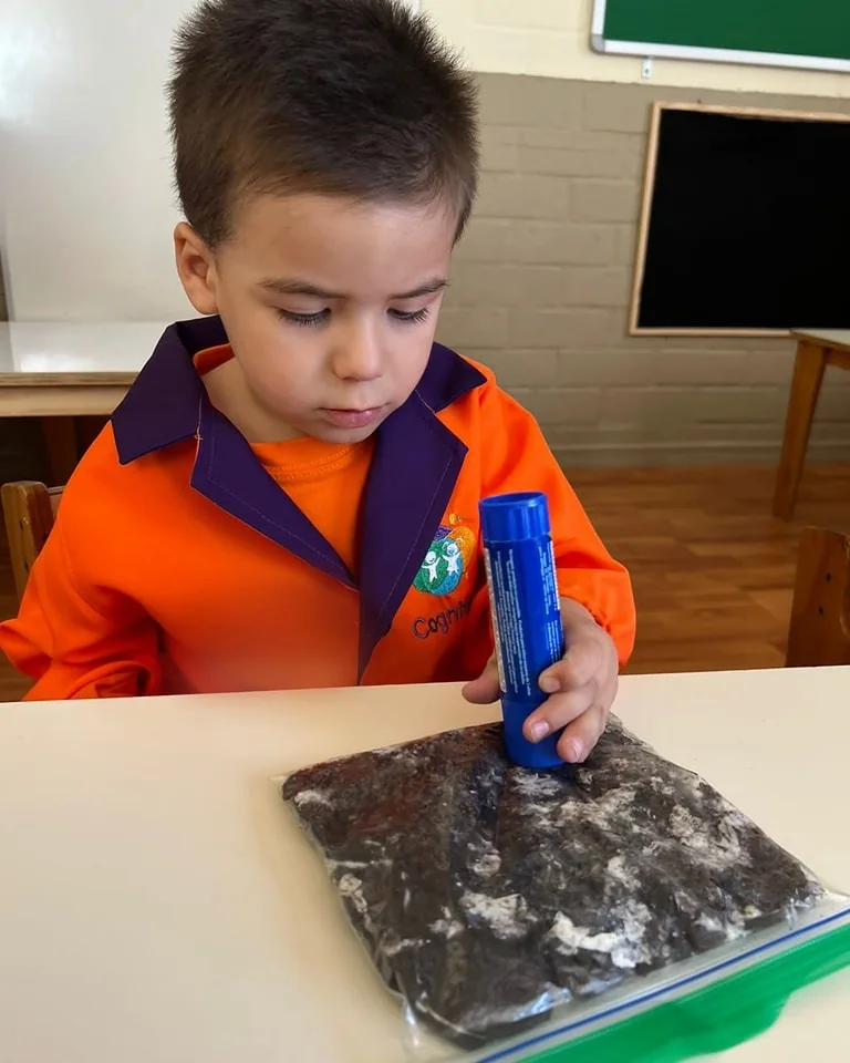 Un niño del jardín trabaja concentrado con una bolsa sensorial sobre la mesa