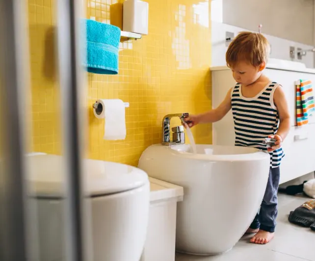Un niño pequeño se lava las manos en el lavamanos del baño