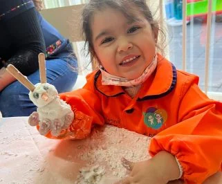Una niña amasa harina con las manos en la mesa de trabajo sensorial